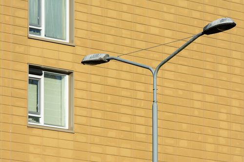 Free A street lamp in front of a yellow building with windows, showcasing urban architecture. Stock Photo