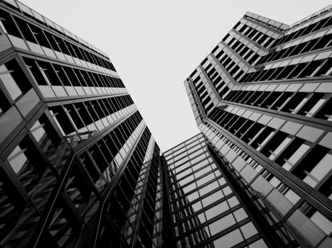 Striking black and white perspective of modern urban architecture with geometric glass elements.