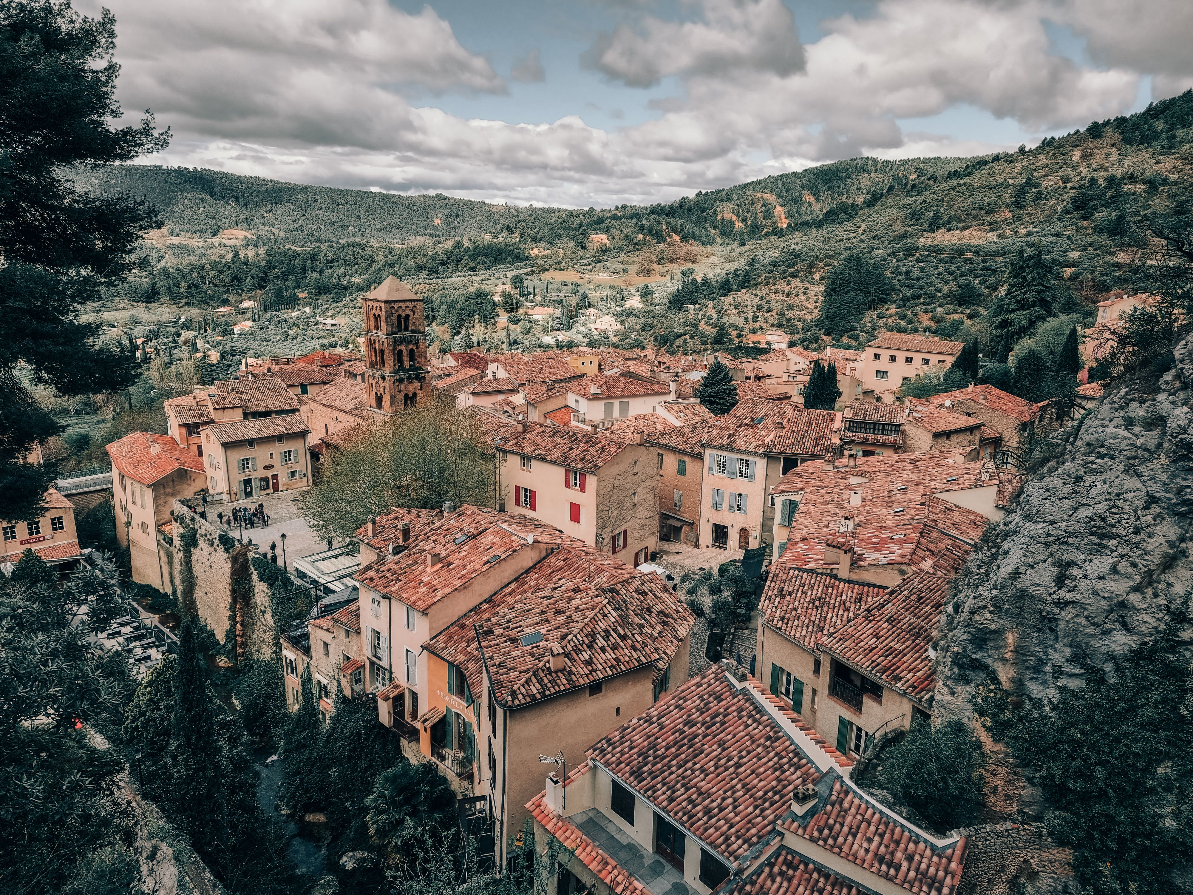 A picturesque aerial view of a quaint French village with red-tiled roofs and lush landscape.