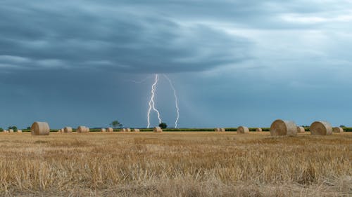 Lighting over Farm Field with Bales of Hay