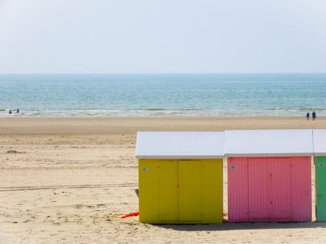 Vibrant beach huts on a sunny sandy coastline, perfect for a summer vacation.