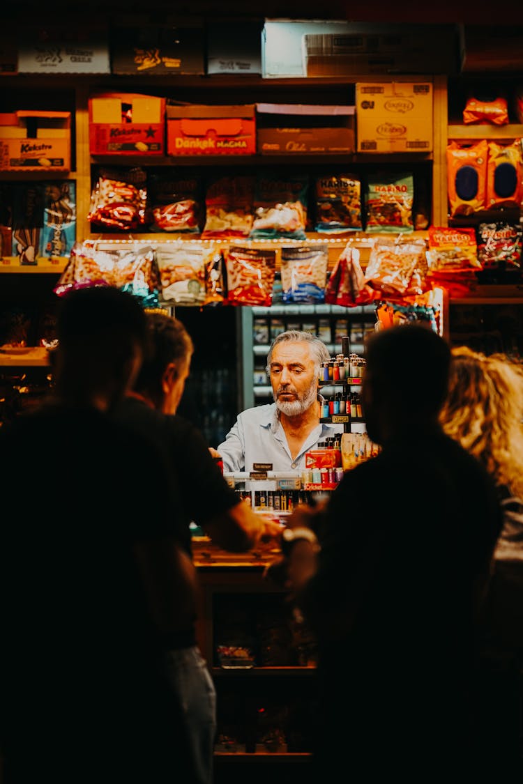 Salesman Standing At Counter In Store