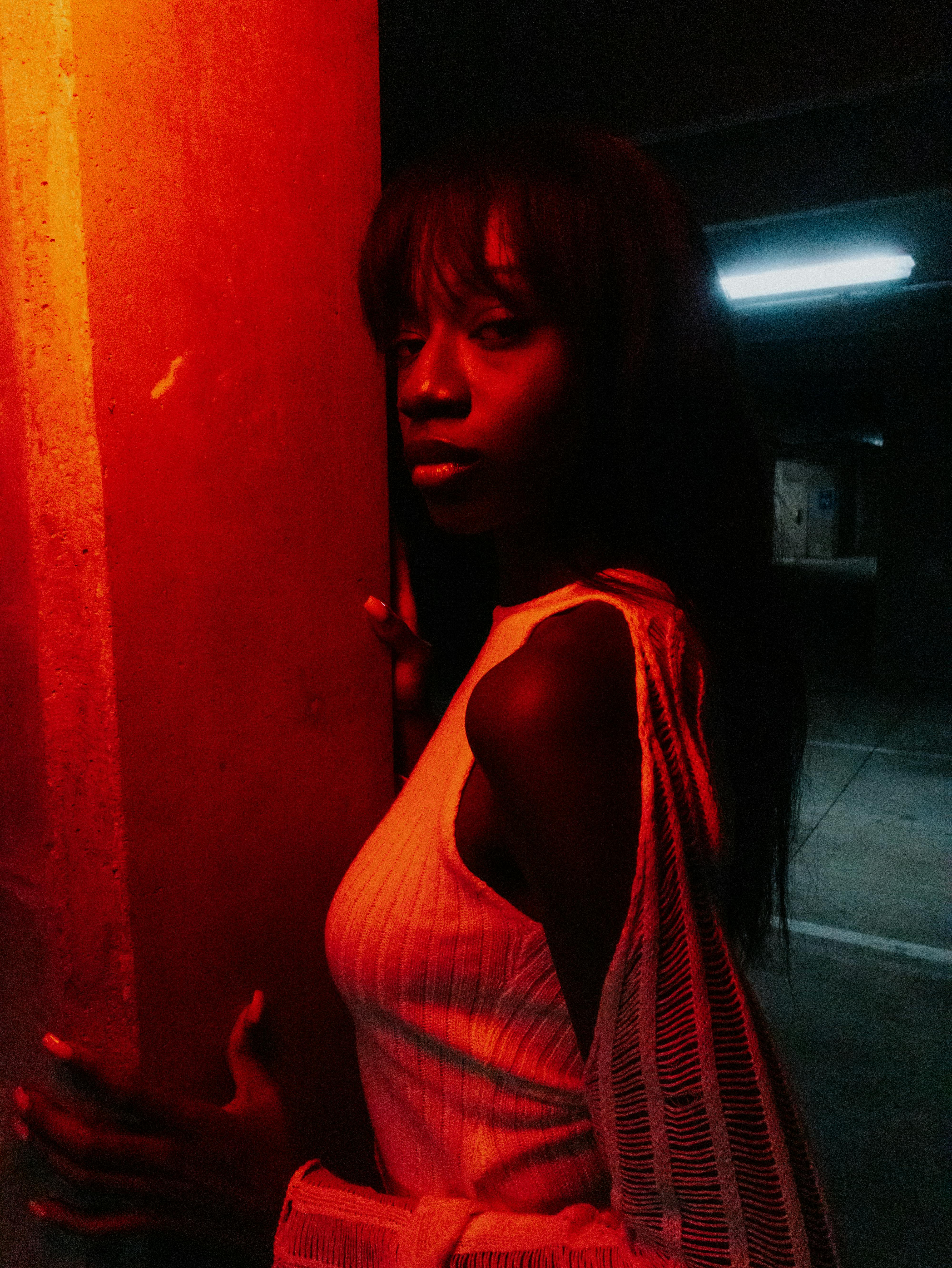 Artistic portrait of a woman posing in a dimly lit parking garage with red lighting.