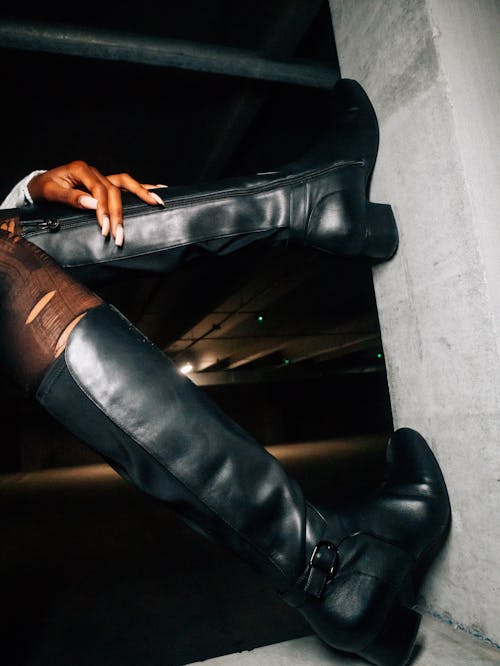 Legs of a Model Wearing Knee-high Leather Boots and Torn Stockings