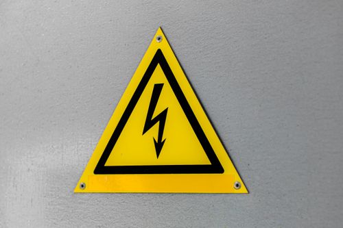 Free Close-up of a yellow high voltage warning sign mounted on a wall. Stock Photo