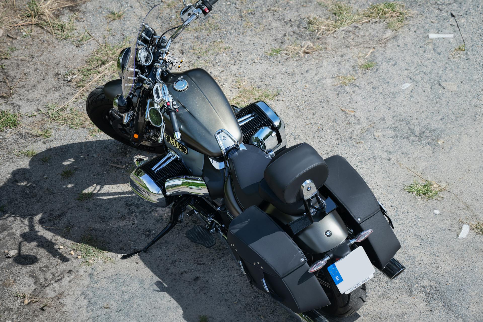 A high-angle shot of a sleek cruiser motorcycle parked on a dusty road.