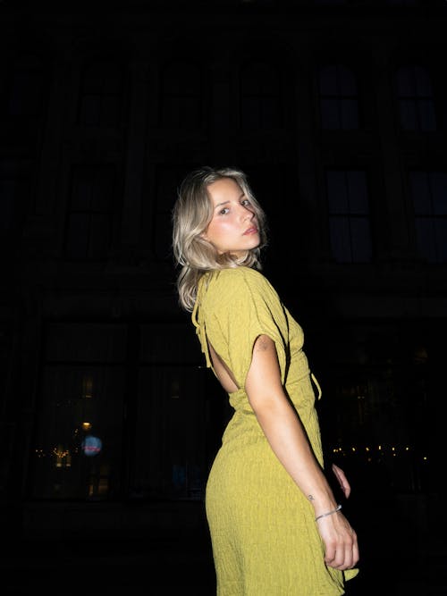 Young Woman in Yellow Open Back Dress on the Sidewalk at Night