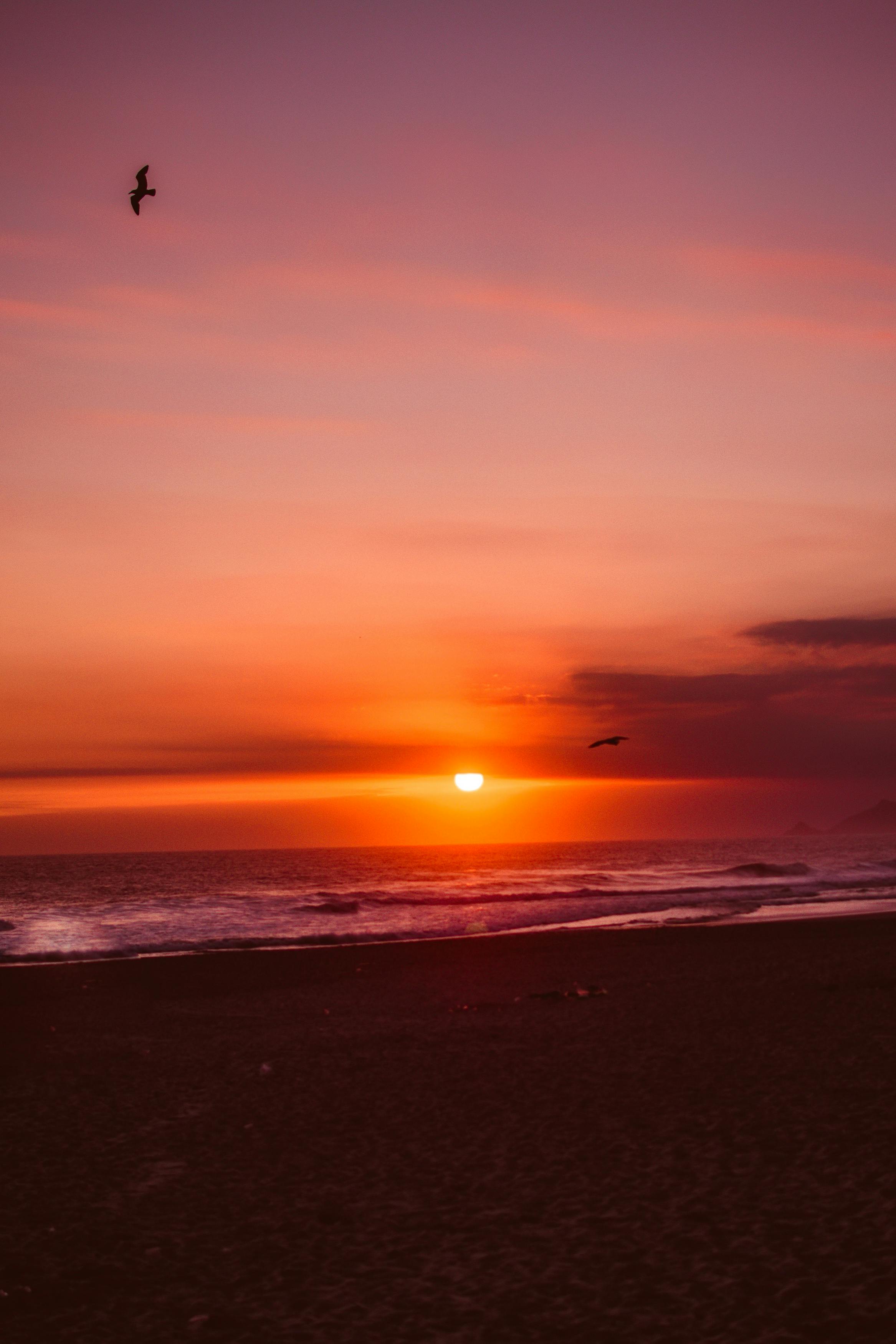A breathtaking sunset over the ocean with waves and vibrant sky colors.