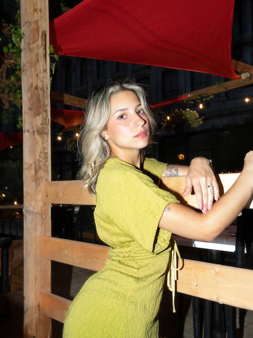 Young Model in a Lime Green Dress Posing by a Restaurant at Night