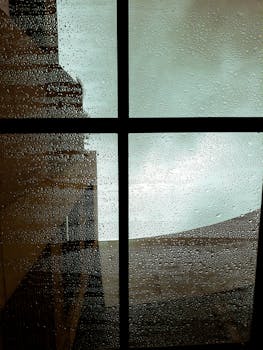 透过窗户，可以看到雨天的景色，有雨滴和城市景观