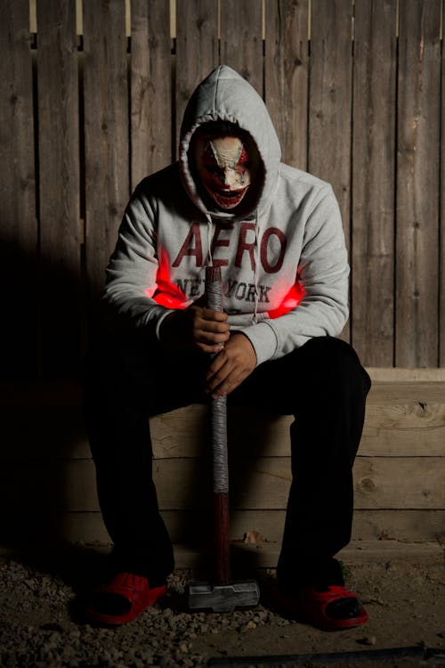 Person with Face Mask Sitting with Hammer in Hands