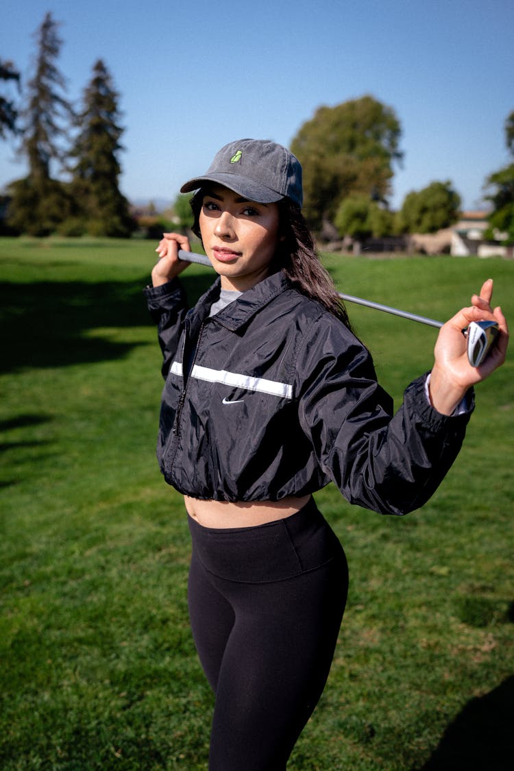 Woman In Cap And Jacket Standing With Golf Club