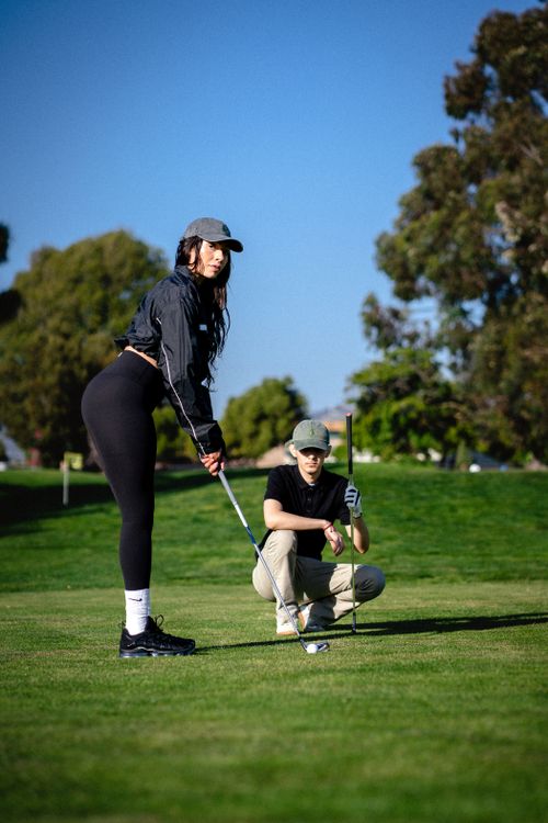 Free Two golfers prepare for the next shot on a sunny course, surrounded by greenery. Stock Photo