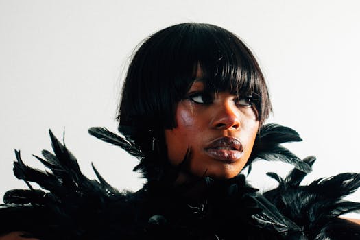 Stunning portrait of a black woman with short hair adorned with feathers, against a white background.