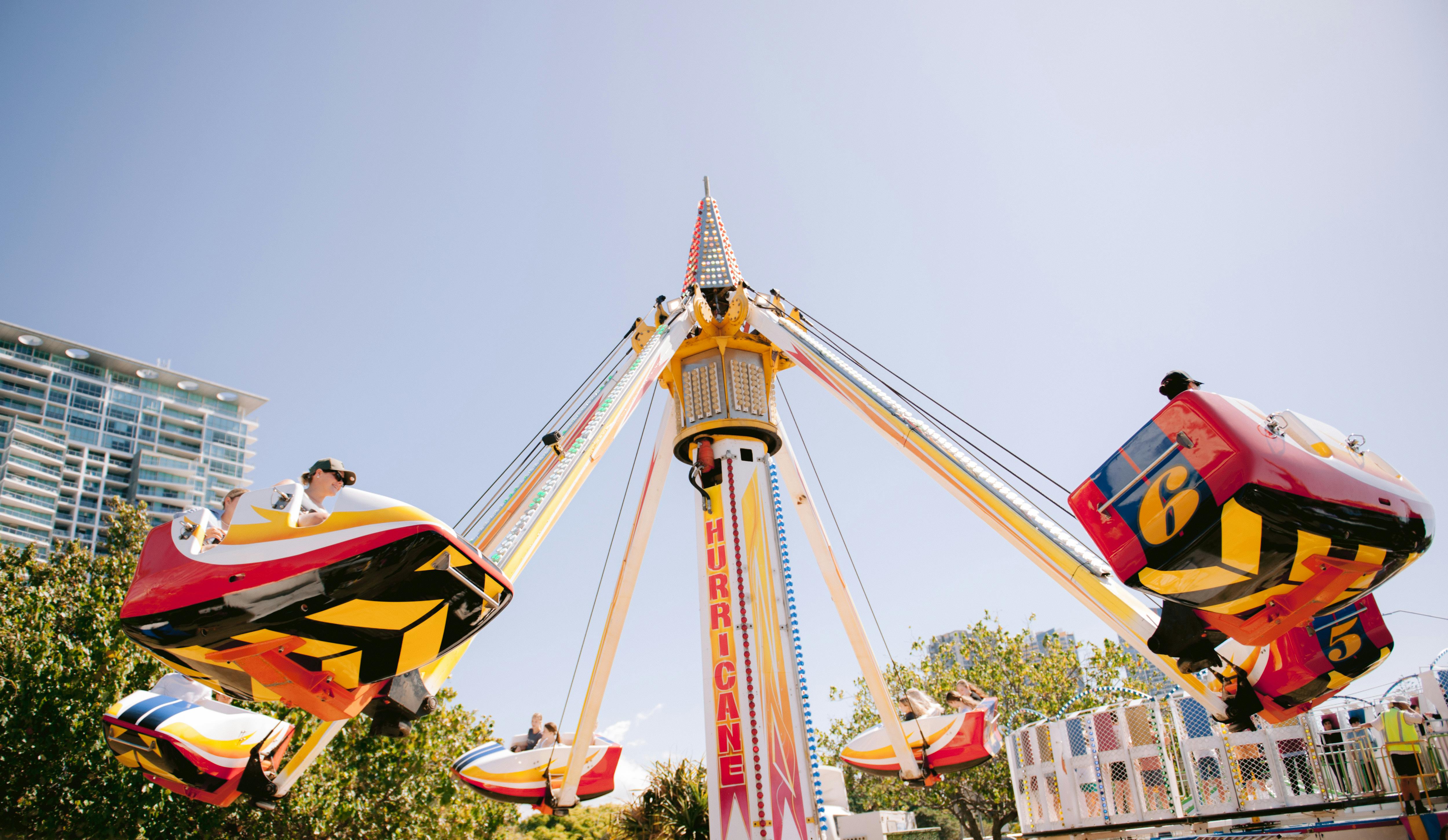 Exciting amusement park ride 'Hurricane' spinning under bright blue sky, capturing fun and adventure.