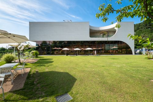 Free A modern cafe exterior with a spacious patio and lush green lawn, perfect for leisure and tourism. Stock Photo