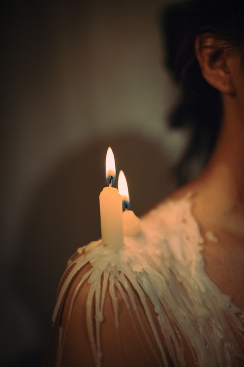 Free A creative shot of burning candles with wax on a person's shoulder. Perfect for artistic and conceptual themes. Stock Photo