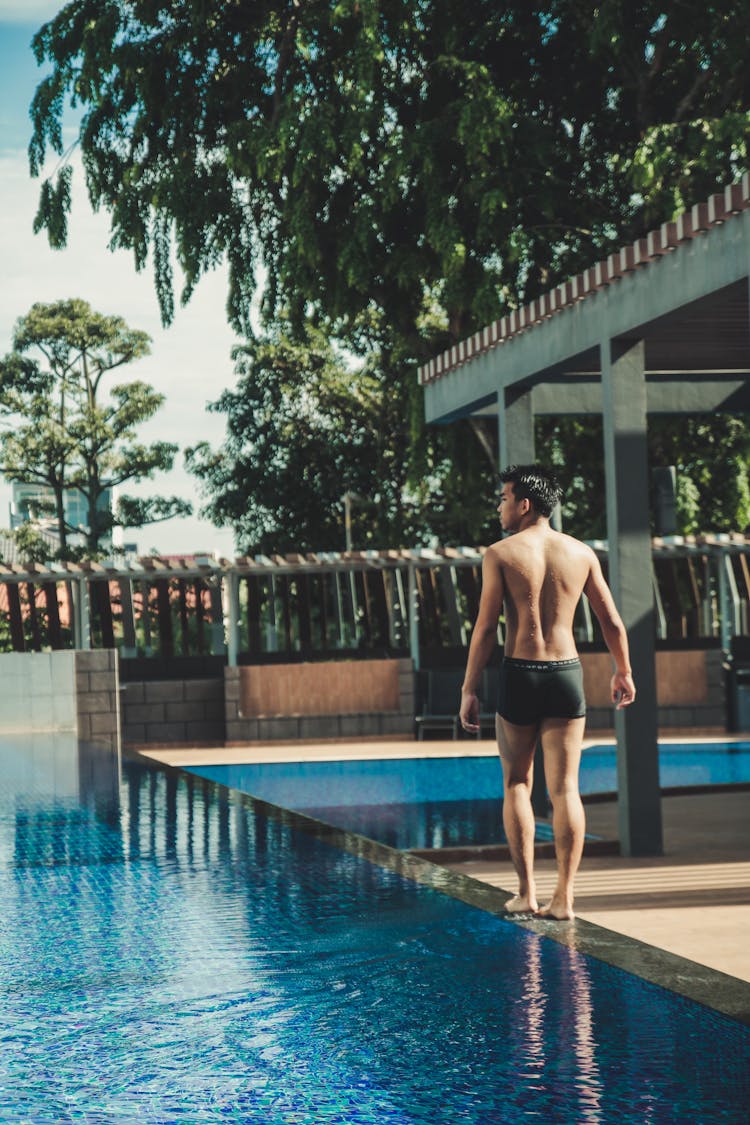 Young Man Walking By The Swimming Pool In A Resort