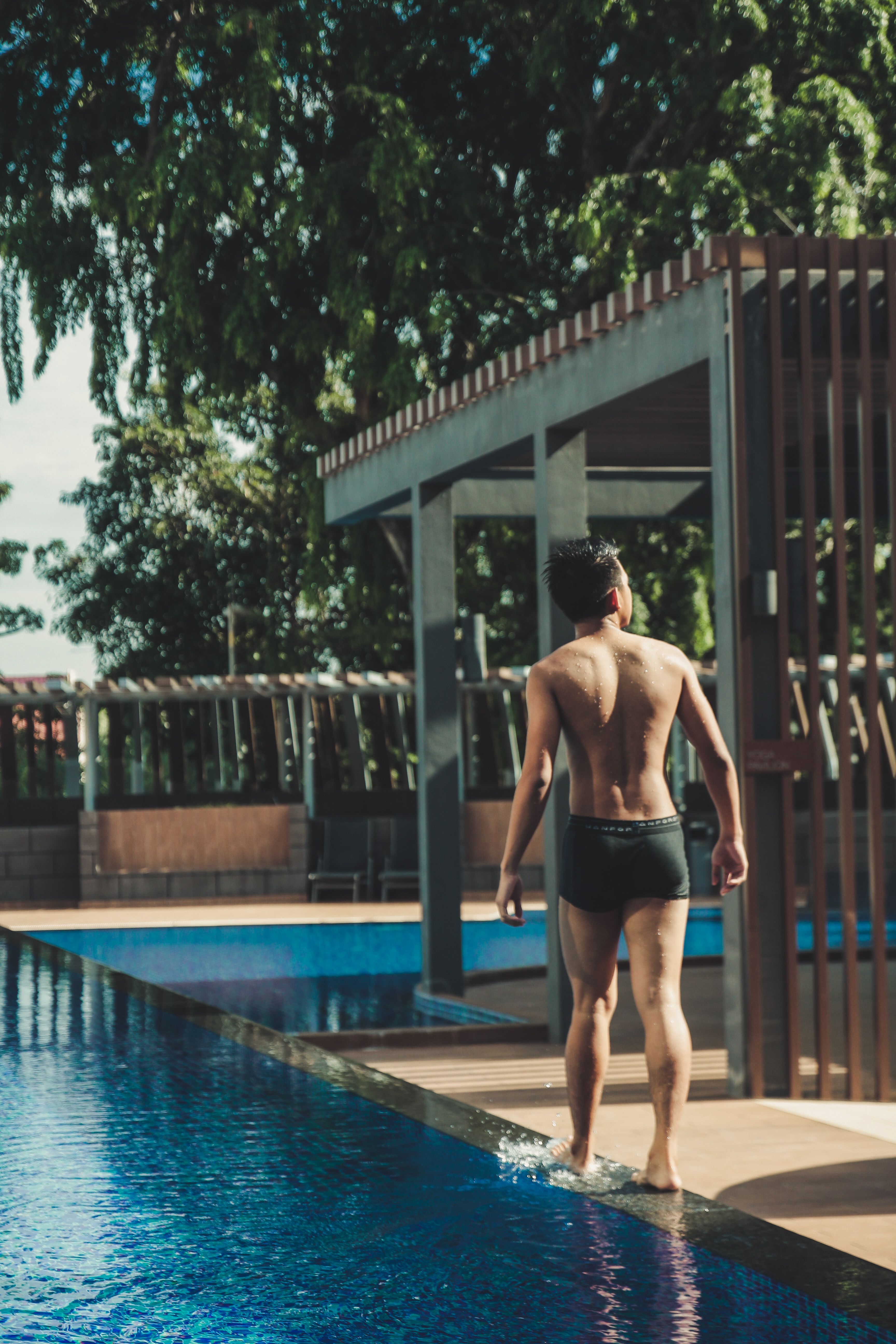 Young Man Walking By a Swimming Pool in the Resort · Free Stock Photo