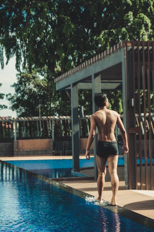 Young Man Walking By a Swimming Pool in the Resort