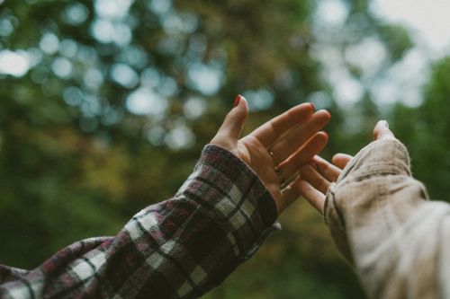 Free Two friends reaching out to each other in a cozy autumn park scene, wearing flannel. Stock Photo