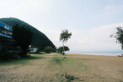 Free Serene beach scene with a mountain view and calm sea, perfect for relaxation. Stock Photo