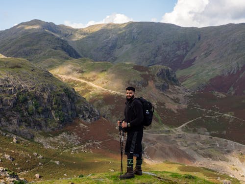 Photo of a Hiker with a Backpack and Trekking Poles in Mountains