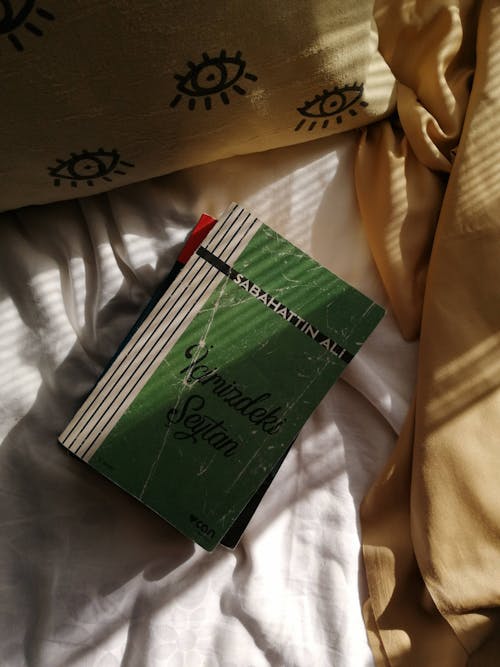 Photo of a Green Book on the Creased Bedding