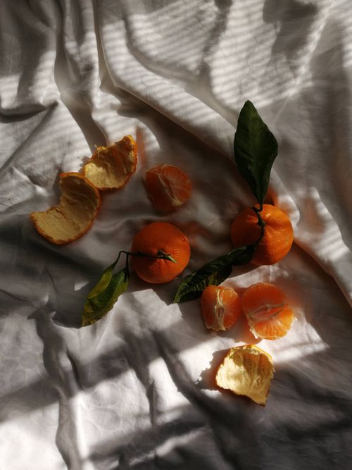 Free Artistic still life with tangerines and light play on draped fabric. Stock Photo