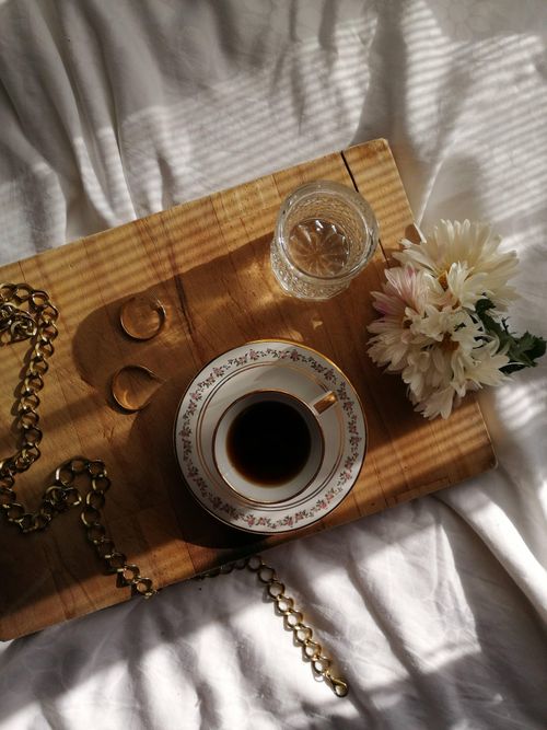 Free Aesthetic flat lay of coffee, flowers, and jewelry on a wooden tray with soft light. Stock Photo