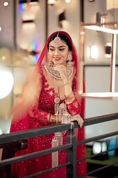 Portrait of a smiling bride in vibrant red traditional attire and jewelry.