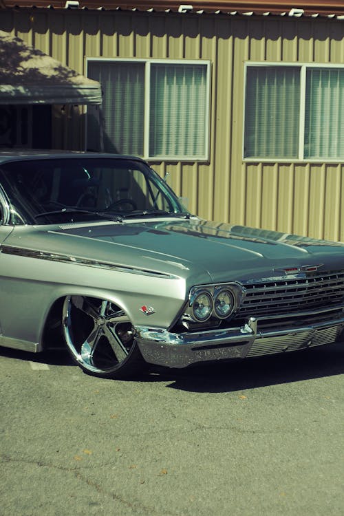 Photo of a Silver Vintage Car Parked by a Metal Hut