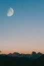 黄昏时分，晴朗的天空中挂着一轮大月亮，映照着美丽的山景