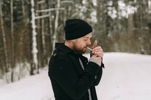 Man Lighting Cigarette in Forest in Winter