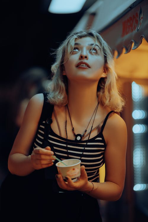 Young Woman Eating Ice Cream Looking Up