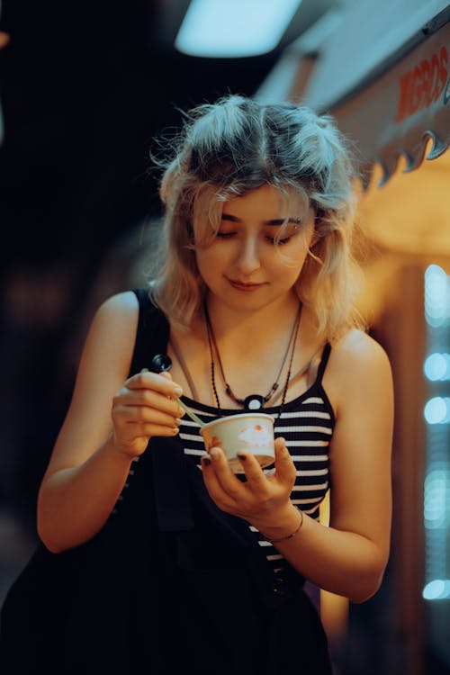 Young Woman Eating Ice Cream from a Cup