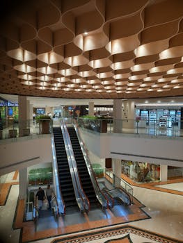 A modern shopping mall interior featuring elegant lighting and escalators in a spacious setting.