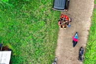 航拍照片捕捉了人们在一条绿树成荫的乡村道路附近聚集，享受户外休闲时光的场景