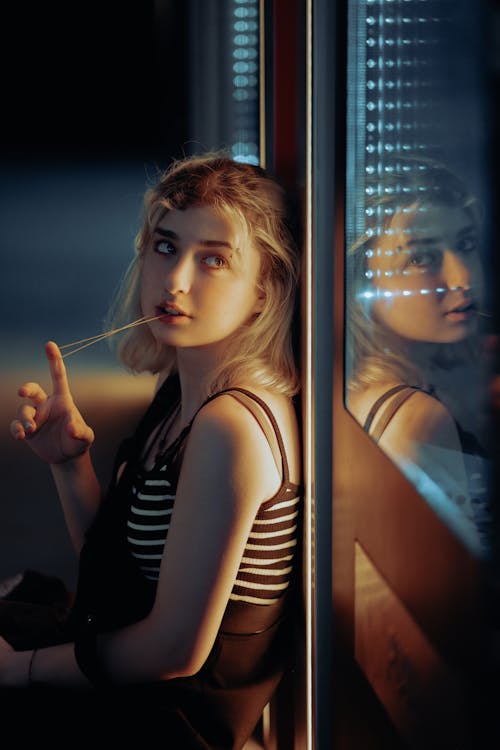 Blonde Woman Standing near Window at Night
