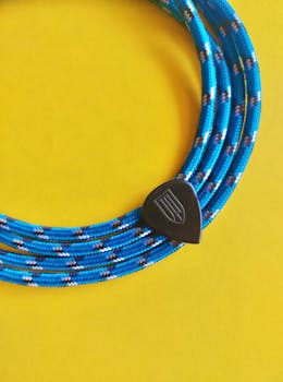A blue climbing rope coiled neatly on a vibrant yellow background, perfect for adventure themes.