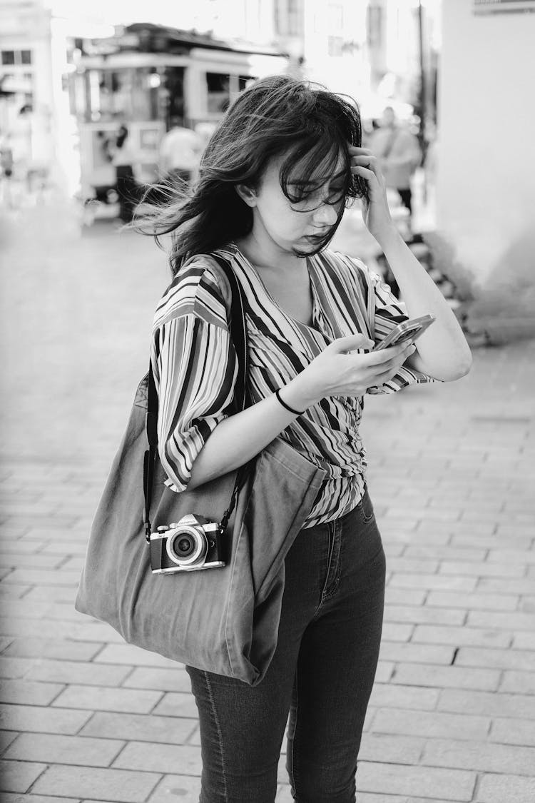 Tourist Woman With Phone And Camera On The City Promenade