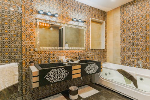 Double Sink and a Glass Bathtub in a Bathroom Lined with Decorative Tiles