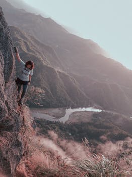 女登山者在陡峭的悬崖上攀登，下方是美丽的山谷景观