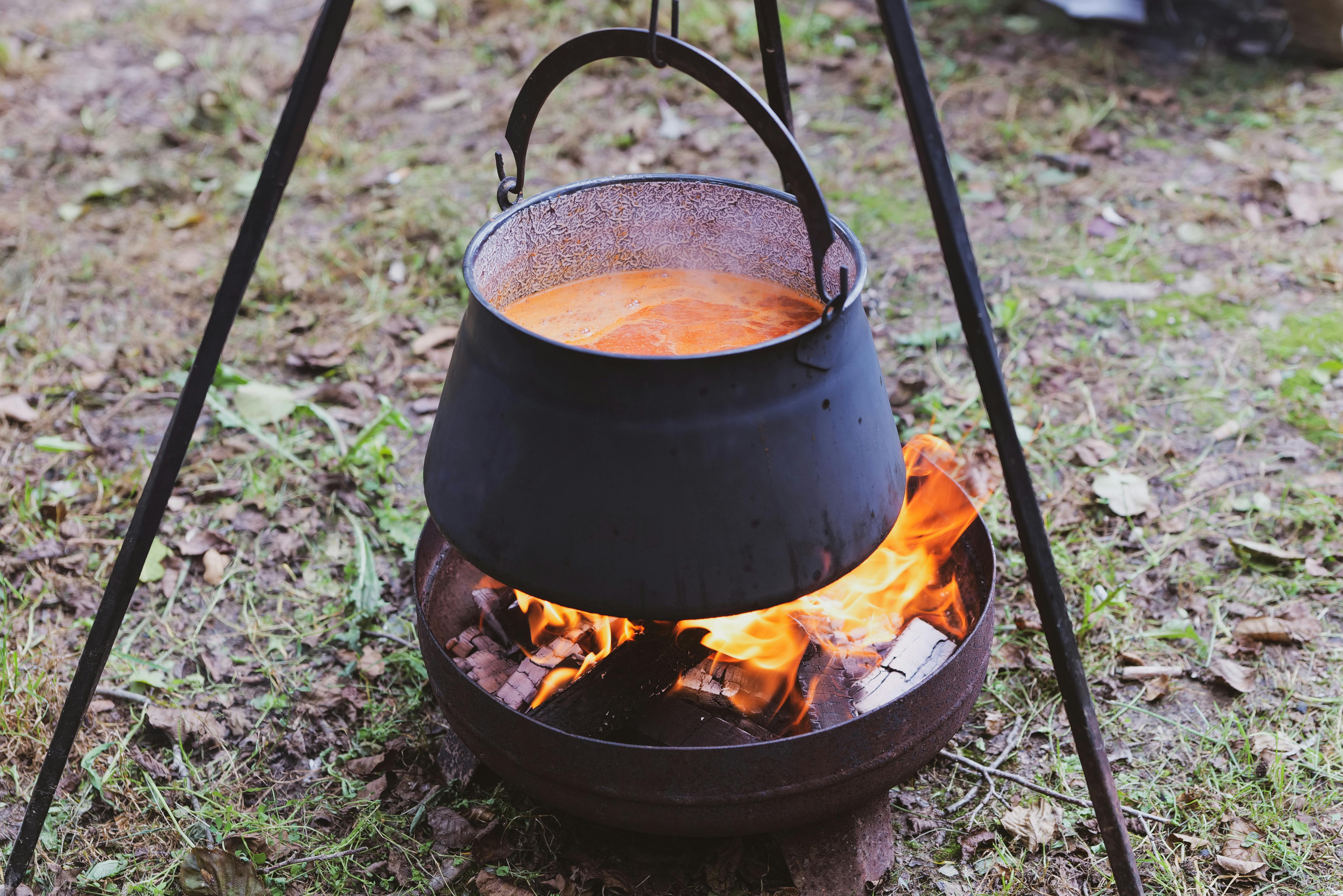 Cooking soup in cast iron boiler on burning campfire. Pot with soup over  the open fire outdoors. Tourism in Latvia. Cooking soup in a pot on  campfire Stock Photo - Alamy