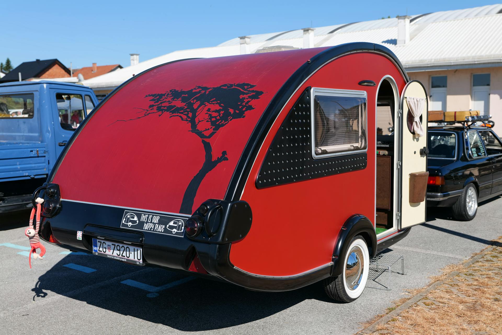 A vibrant red trailer in an urban parking lot with custom design, showcasing modern camping lifestyle.
