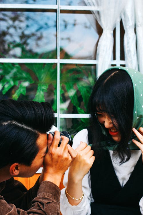 Anonymous Asian couple taking photos on street