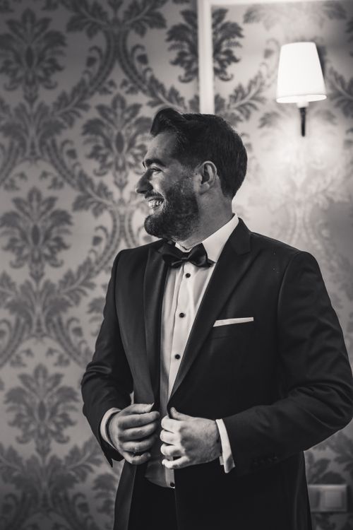 Free Stylish groom in tuxedo smiling joyfully in elegant black and white portrait. Stock Photo