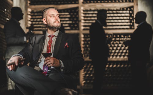 Man in Suit Sitting with Wine