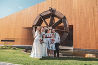 Family in traditional attire poses by a wooden windmill on a sunny day.