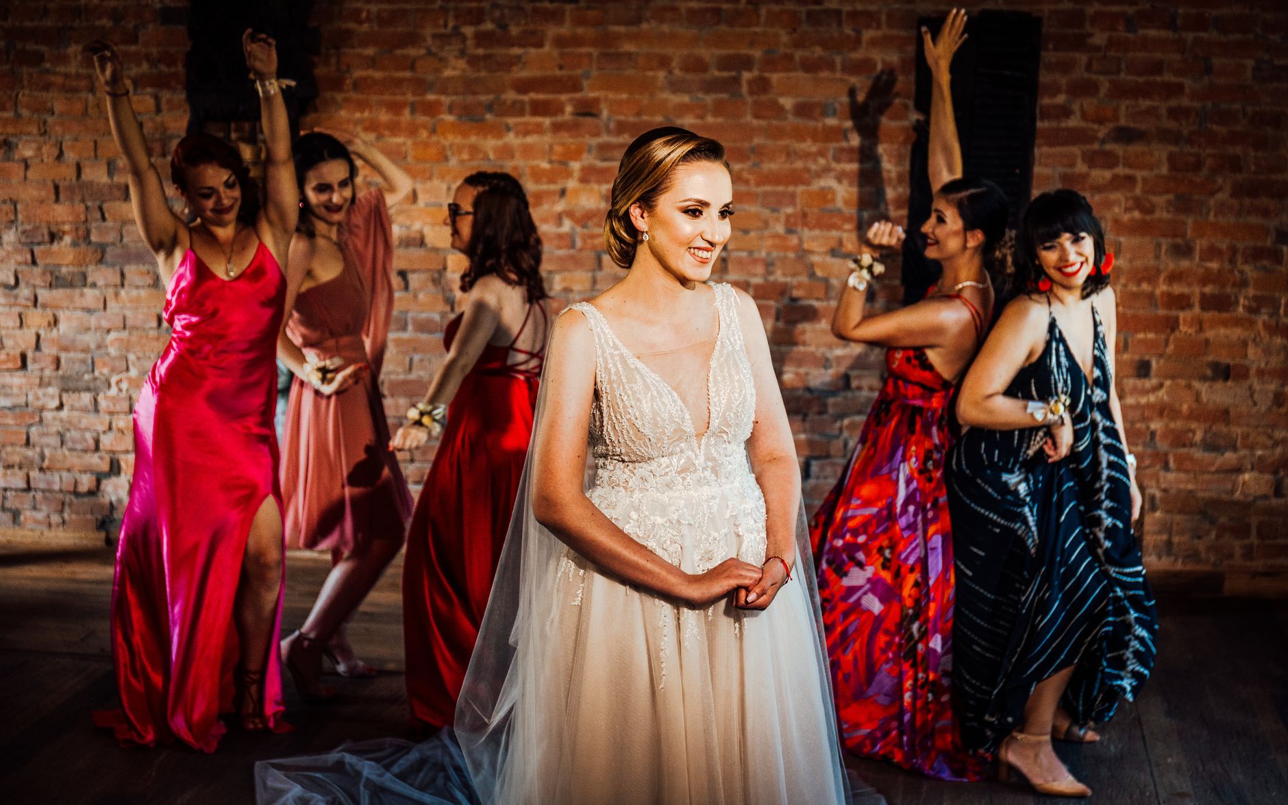 A happy bride with bridesmaids in colorful dresses celebrating indoors.